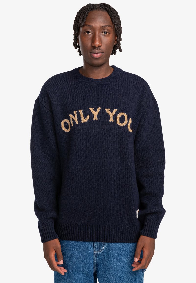Marinblå stickad tröja med "ONLY YOU" i beige text, rundad hals, ribbade muddar och nederkant. Mjuk yta och oversized passform.