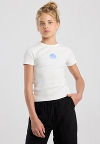 White ribbed short-sleeve T-shirt featuring a blue graphic reading "BLUE HORIZON SURF CLUB" on the chest, paired with black pants.