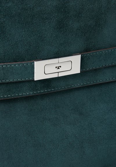 Teal ruskindshåndtaske med et rektangulært sølvlås med et indgraveret logo, suppleret med en syet læderkant.
