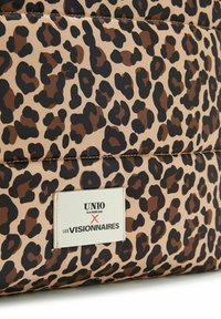 Pochette à imprimé léopard avec un fond beige, des taches noires et brunes, comportant une étiquette blanche avec du texte noir. Texture lisse, design rembourré.