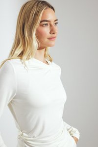 White long-sleeve top with a draped neckline and twisted detail at the waist, made from smooth fabric, featuring a fitted silhouette.