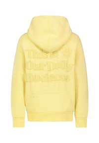 Geel hoodie met een gestructureerde grafiek op de rug, voorzien van reliëf tekst en logo. Het materiaal lijkt zacht, met ribbels aan de manchetten en onderkant.