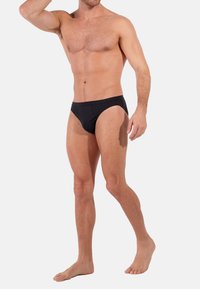 Schwarze Herren-Schwimmslips mit niedrigem Schnitt, glatter Textur und minimalistischem Stil. Sie verfügen über eine einfarbige Gestaltung und einen elastischen Bund.