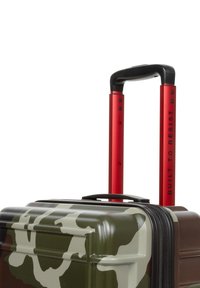 Hård resväska med ett kamouflage-mönster i grönt, brunt och krämfärgat. Har ett rött teleskophandtag och en texturerad yta.