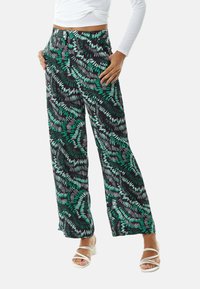 Black wide-leg pants featuring a colorful leafy pattern in green and white, made from lightweight fabric with an elastic waistband.