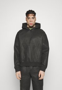 Sudadera gris texturizada con bolsillo canguro y capucha con cordón. Puños y dobladillo acanalados, combinada con pantalones a juego.