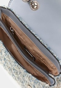 Borsa a tracolla sintetica azzurro chiaro con un esterno in tweed blu morbido e strutturato, dotata di un ampio interno che include due scomparti e una chiusura metallica.