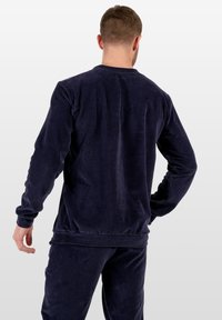 Sudadera de cortas de pana en color marino con mangas largas, textura acanalada y escote redondeado, que presenta un corte holgado y puños elásticos.
