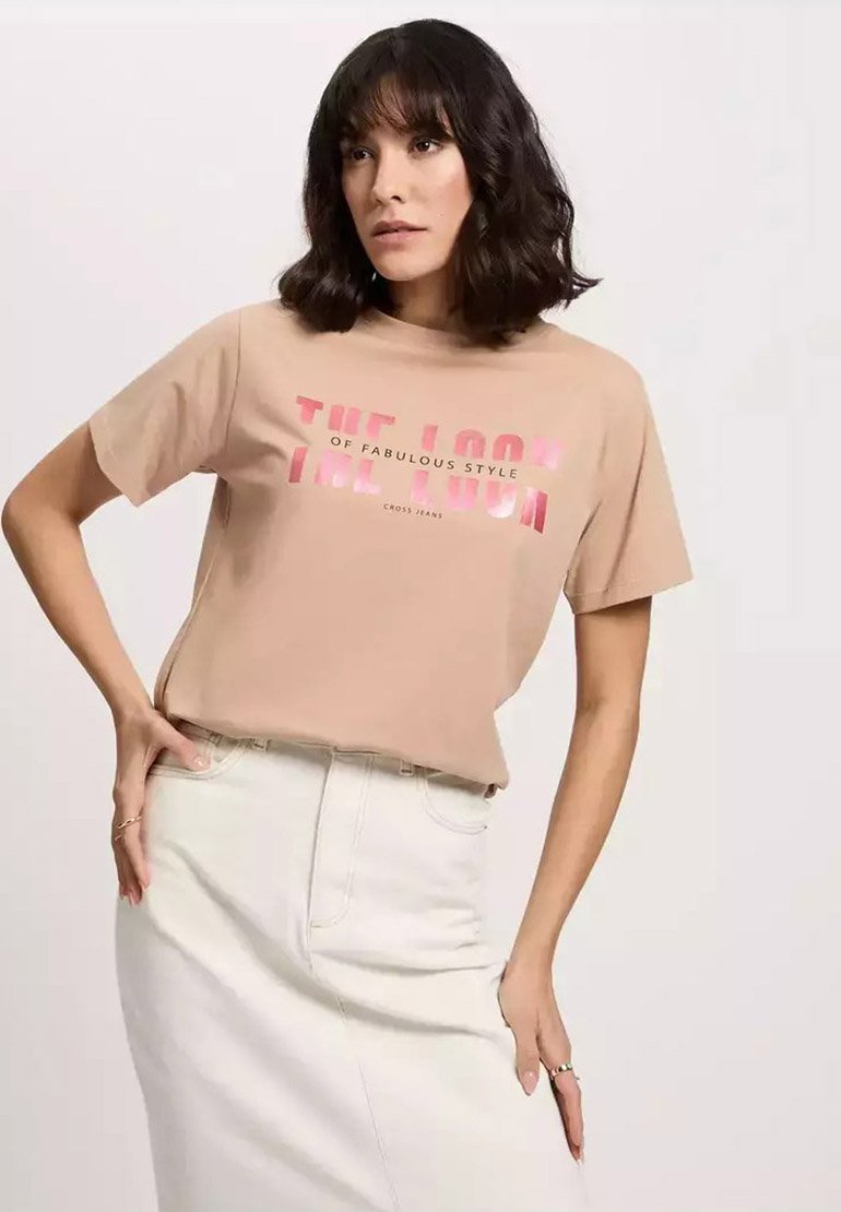 Beżowa bawełniana koszulka z krótkim rękawem i grafiką tekstu w kolorze różowym. Połączona z białą dżinsową spódnicą o wysokim stanie. Luźny krój.