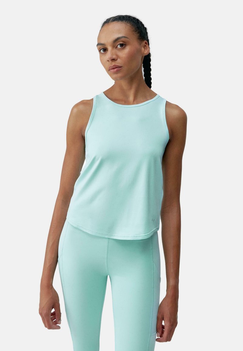 Mintgroene mouwloze sporttop met een ronde halslijn en een relaxte pasvorm. Glad oppervlak met een lichte glans. Gekocht met strakke leggings.