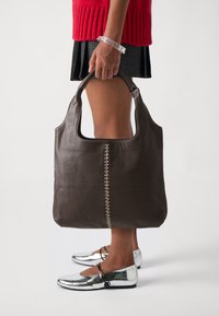 Brown leather handbag with a simple design, featuring a decorative stitch along one side. Handle attached for carrying.