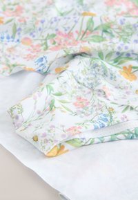 Tessuto bianco con un motivo floreale colorato, con vari fiori in rosa, viola e arancione, dalla trama morbida e finitura liscia.