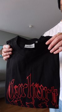 Black cotton T-shirt featuring red stylized "Carhartt" text at the front. Standard crew neck and short sleeves.