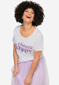 Hvid t-shirt med korte ærmer, med teksten "choose happy" i lilla, iført en lys lilla tylskørt, der viser en afslappet pasform og glat tekstur.