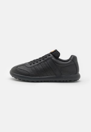 Schwarze Ledersneaker mit geriffelten Akzenten, runder Zehenpartie, Schnürung vorne, strukturiertem Boden und dezentem Logo an der Seite.