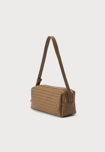 Sac à main en cuir tressé marron de forme rectangulaire avec une longue bandoulière cousue, sur un fond clair uni.