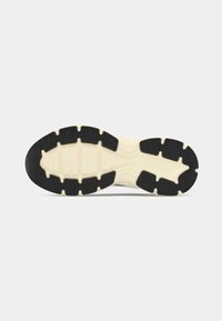 Fekete és krém színű sneaker talp texturált gumival, változó gumimintázatokkal és megerősített orr résszel a tapadás és tartósság érdekében.