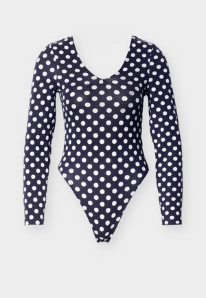 Body bleu marine à manches longues avec de grands pois blancs, présentant un col en V profond et une coupe haute à la jambe. Tissu lisse et extensible.