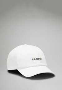 Vit keps i tyg med en rundad skärm och en svart "lululemon"-logotyp på framsidan. Slät yta utan ytterligare mönster.