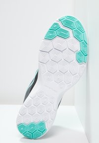 Suela de zapato deportivo con base blanca y patrones de tracción hexagonales en turquesa. Presenta un borde superior negro con textura suave.