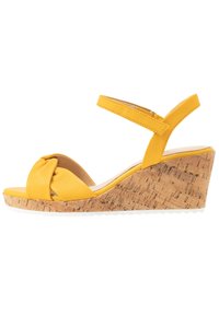 Gula kilklackar med knuten frontdesign, korkkilklack och en smidig ankelrem för en säker passform.