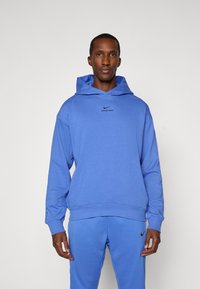 Blue Nike Pro hoodie with a front kangaroo pocket, ribbed cuffs, and logo accent on the chest. Soft fabric with a relaxed fit.