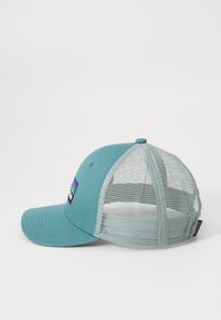 Boné de beisebol teal com aba plana, parte de trás em malha e um patch de logótipo colorido na parte da frente. Tecido macio com um design estruturado.