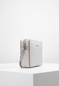 Šedá kožená kabelka přes tělo s texturovaným povrchem, vybavená stříbrným řetízkovým popruhem a zipovým uzávěrem, která se pyšní minimalistickým obdélníkovým designem.