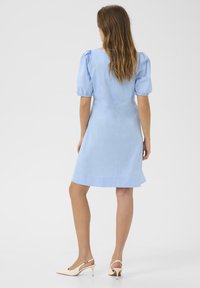 Vaaleansininen mekko puffihälikkäillä, istuvalla bodysuitilla ja hieman levenevällä helmalla. Yhdistettynä vaaleanbeigeihin avokkaisiin. Sujuva kankaan rakenne.