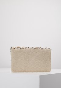 Beige vävd tygclutch med dekorativa pärlor och snäckor längs den övre kanten. Rektangulär design med en texturerad yta.