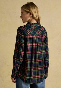 Blue plaid shirt featuring green, yellow, and red lines. Made of soft fabric, with long sleeves, a collar, and button cuffs.