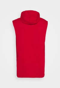 Punainen hihaton huppari, jossa pyöreä, kiristysnauhalla varustettu huppu. Sileä kangas, minimalistinen muotoilu ja suora helma. Ei kuvioita tai muita yksityiskohtia.