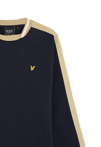 Pull bleu marine avec des accents beiges ; texture côtelée ; présente un petit logo jaune brodé sur la poitrine et un col rond.