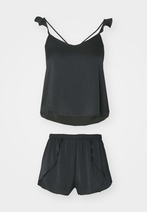 Set da notte nero composto da un top con spalline sottili e dettagli a fiocco, abbinato a pantaloni corti con vita elasticizzata, tasche laterali e una texture morbida.