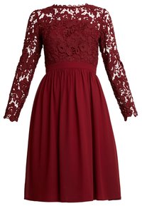 Burgundské šaty s dlouhými krajkovými rukávy a přiléhavým korzetem, přecházející do rozšířené sukně z hladkého materiálu.