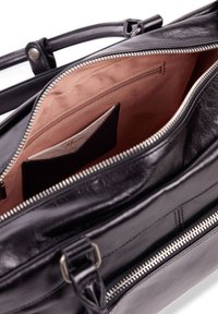 Black leather handbag with silver zipper, featuring a beige fabric interior, a zippered pocket, and a card holder. Sturdy straps included.
