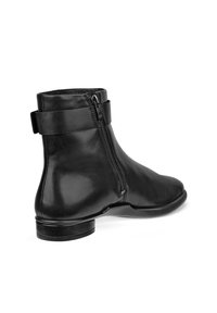 Botte cheville en cuir noir avec une fermeture éclair sur le côté, semelle plate et une bande autour de la cheville. Texture lisse, design minimaliste et forme élégante.
