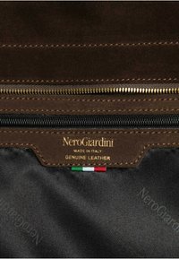 Scomparto con cerniera in suede marrone con dettagli in metallo color oro, con etichetta "NeroGiardini" e un piccolo accento con la bandiera italiana. Pelle autentica.