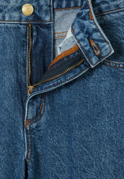 Vaqueros de mezclilla con un zipper dorado, botón superior y costuras de cobre. Presenta una vista en primer plano del zipper y los detalles de la cinturilla.