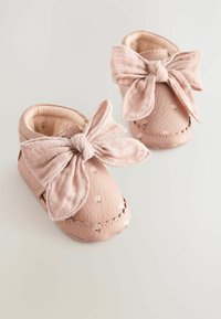 Helle rosa Lederbaby Schuhe mit strukturiertem Finish, featuring eine große Stoffschleife an der Vorderseite und floralen Akzenten an den Seiten.