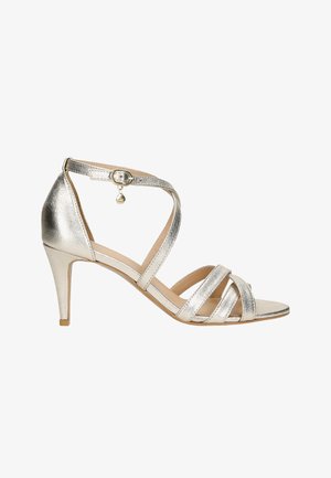 Silberne metallische Absatzsandalen mit überkreuzten Riemen, verstellbarem Knöchelriemen mit Schnalle und Charm-Detail sowie spitzem Zehenbereich.