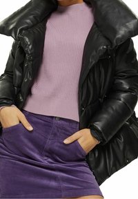 Schwarze Steppjacke mit großem Kragen, geripptem, hellviolettem Pullover und lila Cordrock mit Seitentaschen und Knopfdetail.