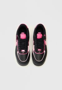 Čierne tenisky Nike Air s ružovými akcentmi, vyrobené z textúrovaného materiálu, s okrúhlou špicou, šnurovaním a výrazným brandingom na jazyku.