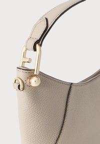 Beežika tooniga tekstureeritud nahast käekott, millel on kuldsed metallosad rihmal ja õmblused mööda äärt.