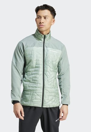 Lichtgroene sweatjack met een quilted structuur aan de voorkant, lange mouwen en zwarte ritsen. Merklogo op de bovenste linkerkant.
