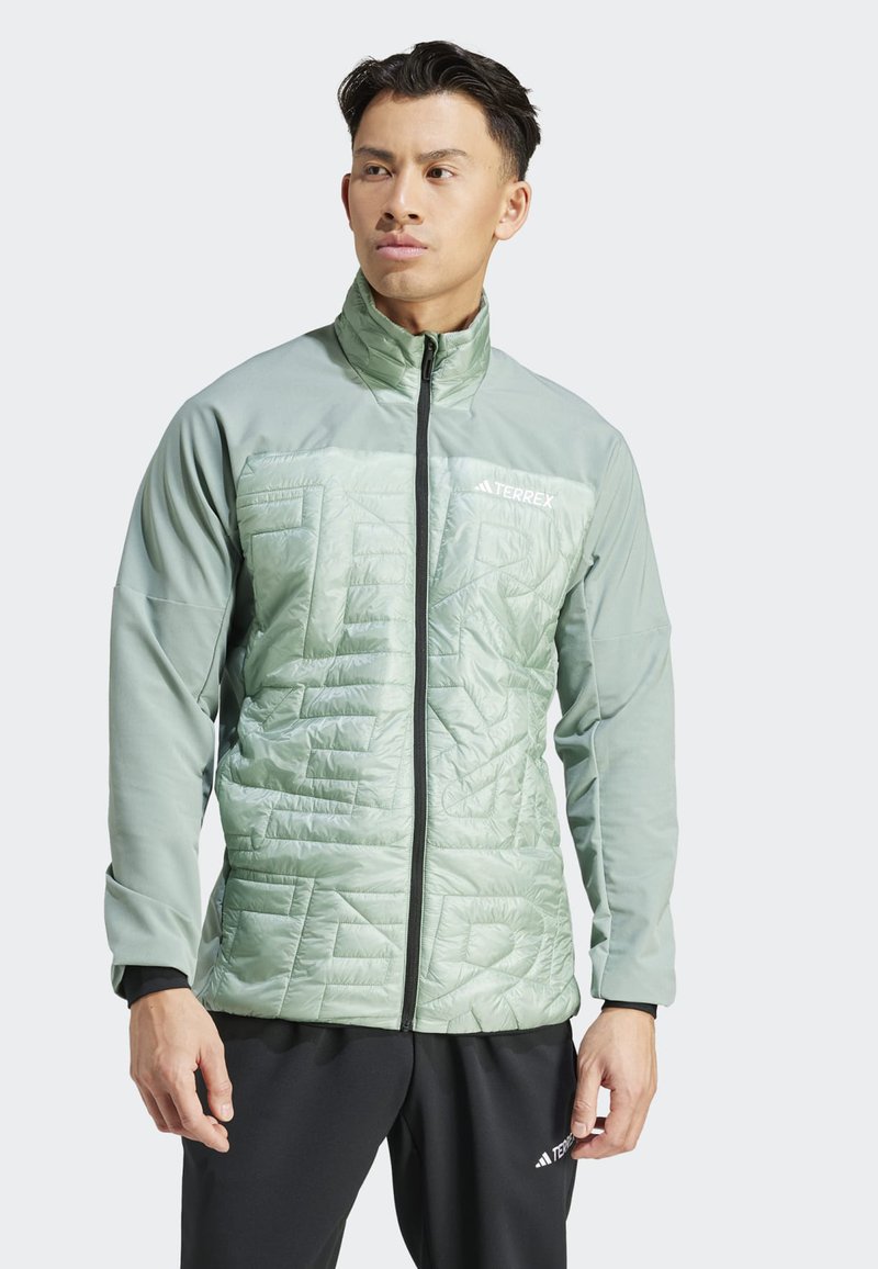 Chaqueta de color verde claro con cremallera, con textura acolchada en la parte frontal, mangas largas y cremalleras negras. Logo de la marca en la parte superior izquierda.