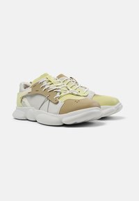 Sneakers featuring a mix of light yellow, beige, and white materials. Chunky sole, combined textures, and accented eyelets with laces.