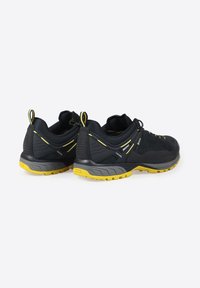 Scarpe da ginnastica nere con accenti gialli; tomaia sintetica, lati testurizzati, colletto imbottito e una suola gialla robusta per la trazione.