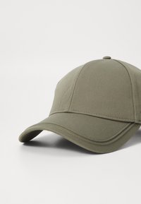 Oliven grønn baseballcap laget av teksturert stoff, med buet skjerm og strukturert krone med sydd detaljer.