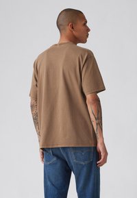 Bruine katoenen t-shirt met korte mouwen, ronde hals en een relaxte pasvorm. Vertoond een gladde textuur en minimale stikdetails aan de onderkant.